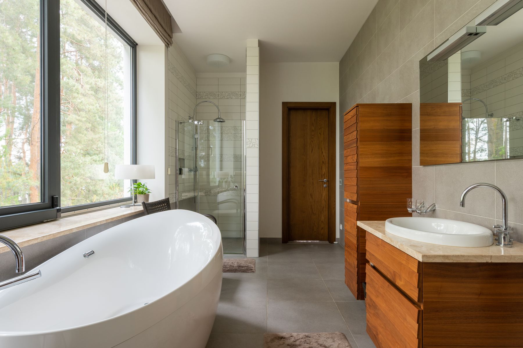 Photograph of a bright bathroom with a freestanding bath, walk-in shower and wooden vanity